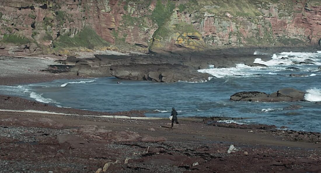 A swimmer runs down a rocky beach in Jonathan Glazer's Under the Skin